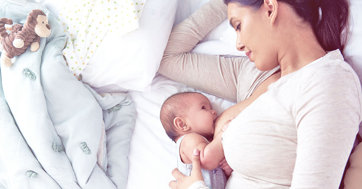 Mutter stillt ihr kleines Baby im Bett