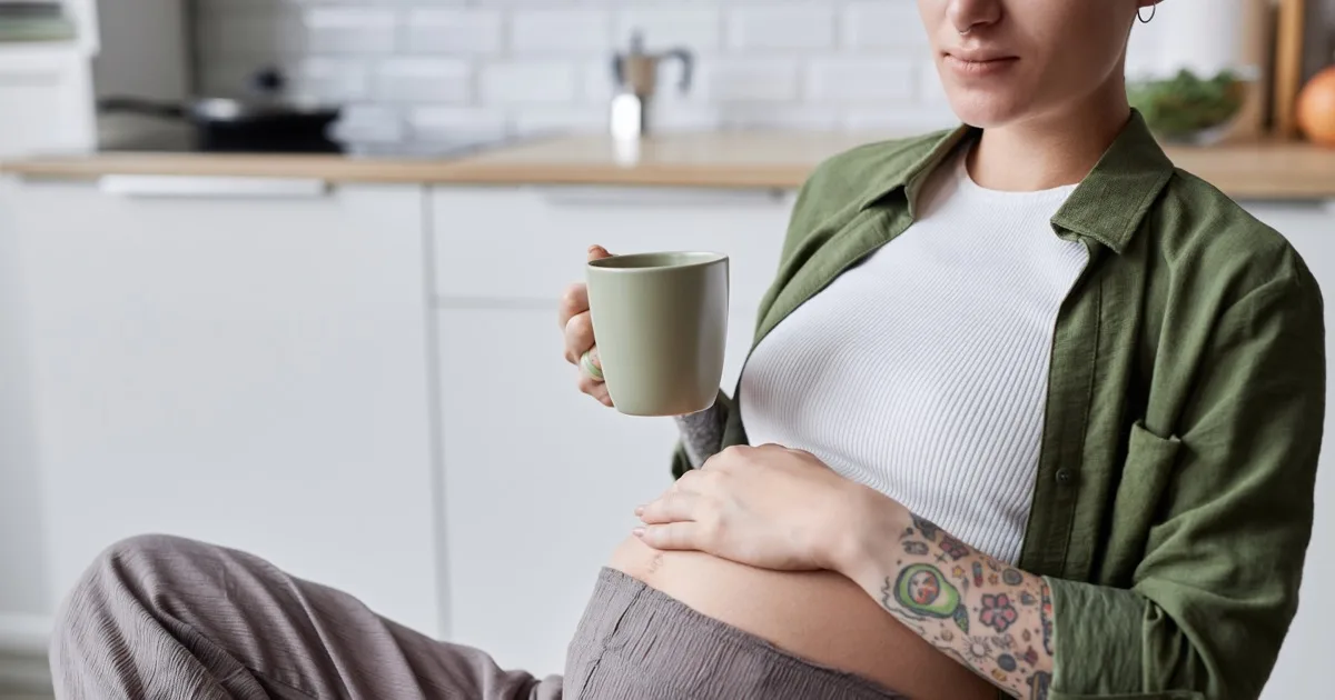 Schwangere Frau entspannt sich mit einer Tasse in der Küche
