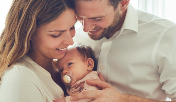 Mutter, Vater und Kind mit Neugeborenem beim Wochenbett