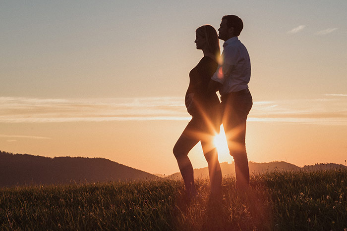 Paar, sie schwanger, im Sonnenuntergang